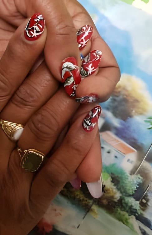 Rode nagels met een wit geschilderd bloemmotief
