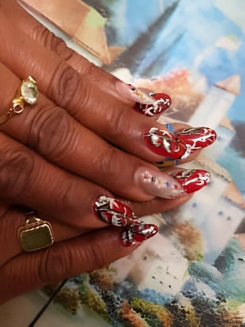 Rode nagels met wit motief en een roze nagel