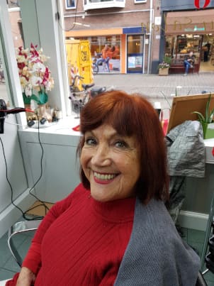 Lachende klant met kort roodbruin geverfd haar in de salon