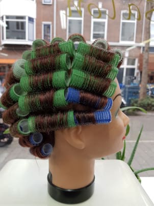 Haar in groene en bruine krulspelden, van opzij